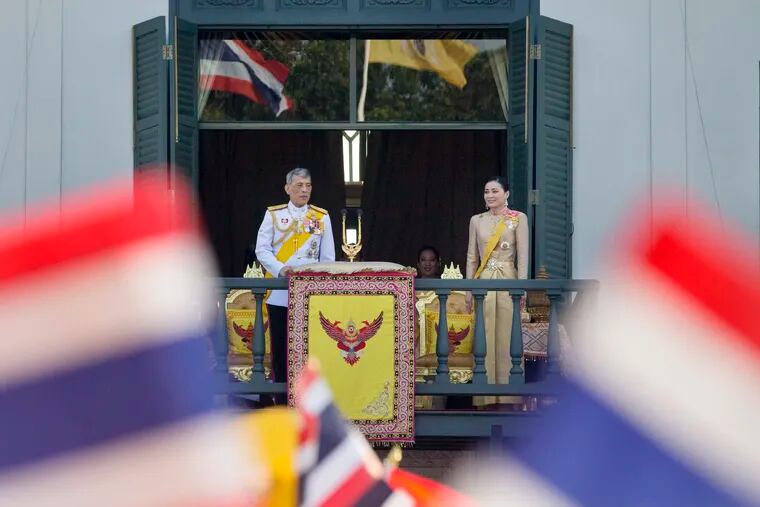 Thailand's King Maha Vajiralongkorn and Queen Suthida are seen through waving national flags as they greet an audience from a balcony of Suddhaisavarya Prasad Hall in the Grand Palace during the King's coronation ceremony Monday, May 6, 2019, in Bangkok, Thailand. Vajiralongkorn was officially crowned amid the splendor of the country's Grand Palace, taking the central role in an elaborate centuries-old royal ceremony that was last held almost seven decades ago. (AP Photo/Gemunu Amarasinghe)