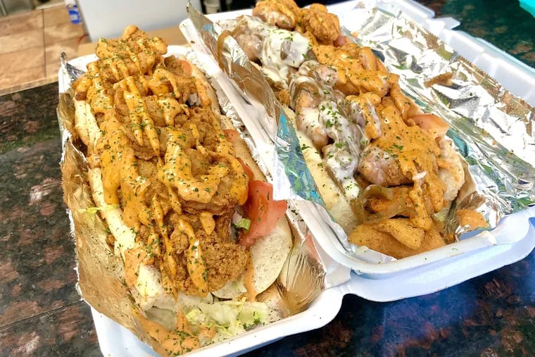 A fried seafood po' boy (left) and fried salmon po' boy (right) with Cajun remoulade sauce, onions and cheese are among the most popular sandwiches at Gilben's Bakery in East Mount Airy.
