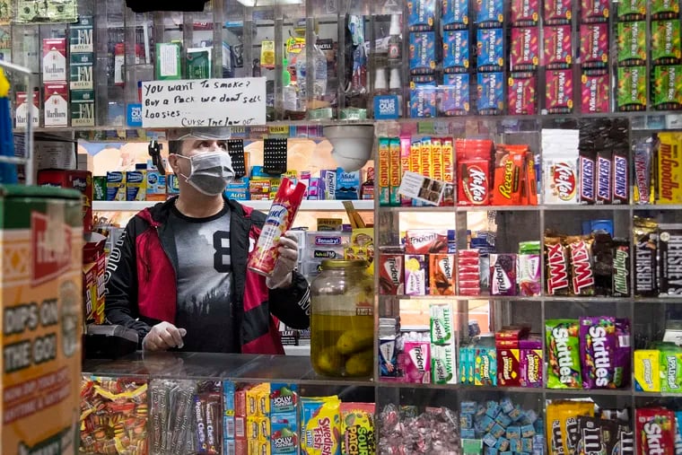 Bodega owner Francisco Peralta holds a canister of Lysol while wearing gloves and a face mask inside his store last week.