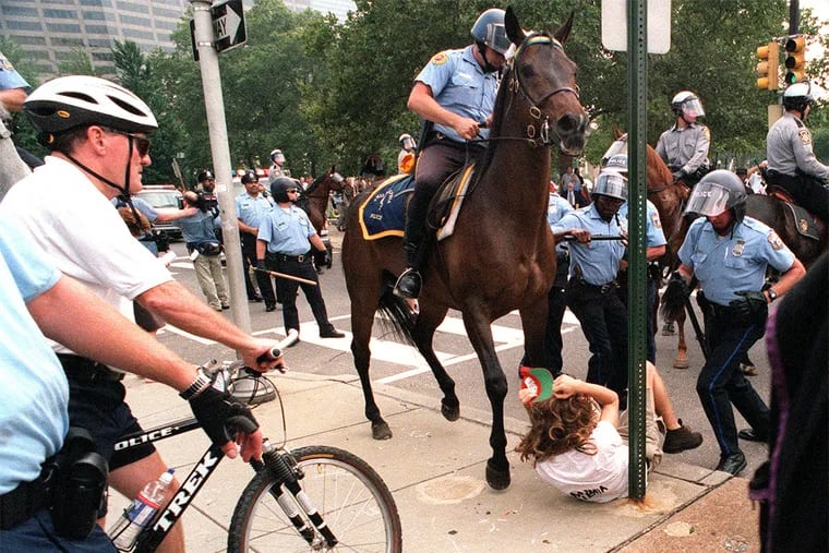 Police commissioner John Timoney, left, looks on as a protester gets trapped under a police horse during a near riot around 18th and Vine Street Tuesday, August 1, 2000. The protester was not seriously injured.