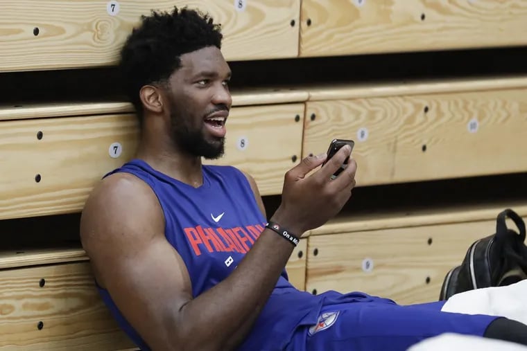 Sixers center Joel Embiid talks on his mobile phone before meeting with the media after practice in Lavietes Pavilion at Harvard University on May 2, 2018.