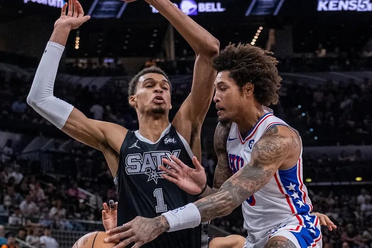 Kelly Oubre Jr. (right) of the Sixers passes the ball as Spurs center Victor Wembanyama defends during the first half.