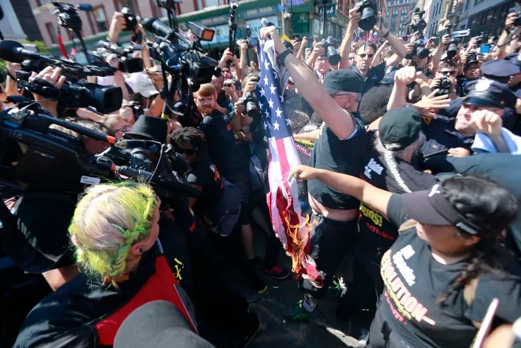 Protesters burn an American flag and scuffle with police officers near the main entrance to the convention.