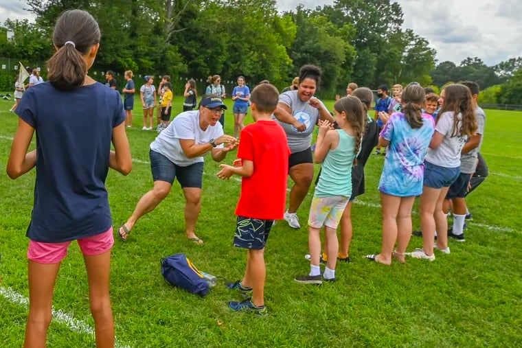 Instructional aide Natalie Dick (left, back) and English teacher Crista Green cheer on students during an "Energy Circle" exercise at Summer Acceleration Camp at Collingswood Middle/High School in Collingswood, N.J., Aug. 16, 2021.