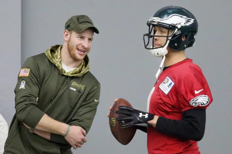 Injured quarterback Carson Wentz, left, talks with current starter Nick Foles during Eagles practice at the NovaCare Complex in South Philadelphia on Saturday, Jan. 27, 2018.