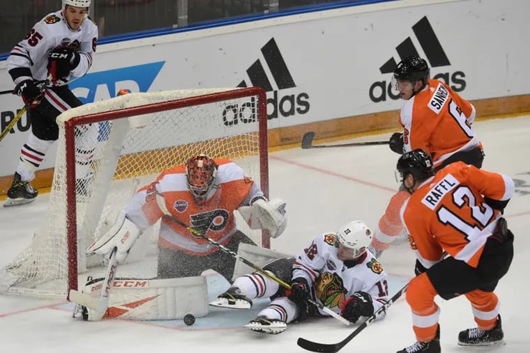 Goalie Carter Hart vies for the puck with Chicago's Alex DeBrincat, while Michael Raffl (12) and Travis Sanheim (far right) converge during the NHL Global Series game Friday, won by the Flyers in Prague, 4-3.