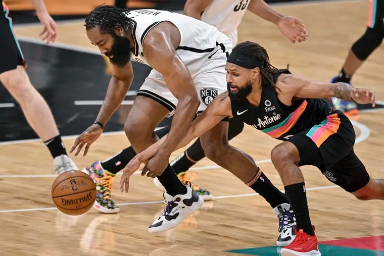 Brooklyn Nets' James Harden, left, and San Antonio Spurs' Patty Mills chase the ball during the first half of an NBA basketball game on Monday in San Antonio, Texas.