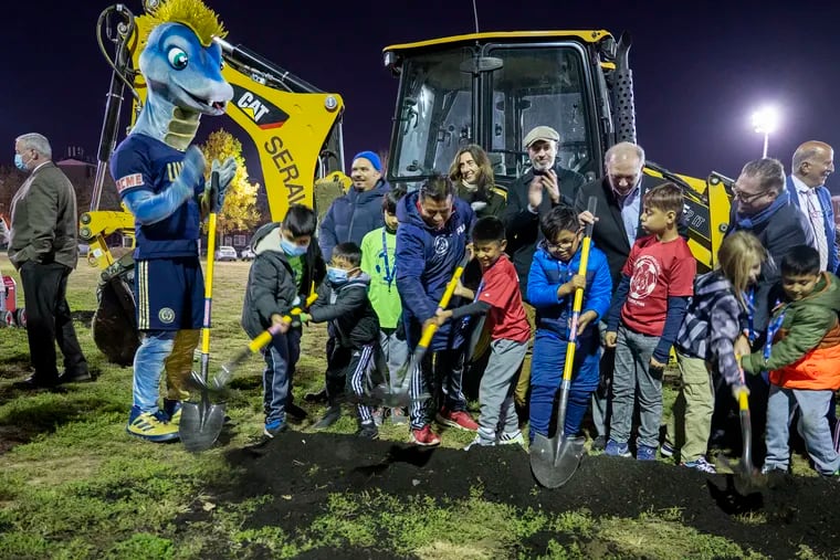 Union mascot Phang (left) helps neighborhood residents shovel dirt during the ceremonial groundbreaking at the Capitolo Playground.