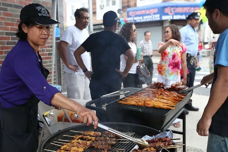 Ira Son (left) grills traditional Cambodian food in South Philadelphia at a festival in early May. There is an effort afoot to officially call the culture-rich area Cambodia Town. ( DAVID MAIALETTI / Staff Photographer )