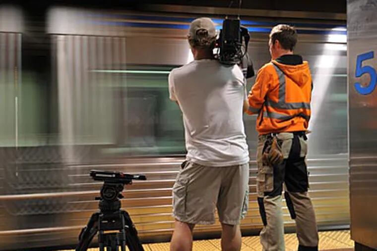 Host Sean Riley and a cameraman watch a SEPTA train pass by. (National Geographic Television)