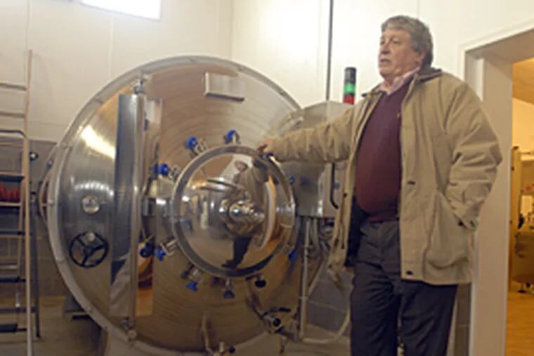 Gino Razzi shows off his rotary fermenter, where crushed grapes undergo their crucial transformation from juice to wine, in his Eddystone facility. He says the machine extracts maximum essence from his fruit. (Ron Tarver/Inquirer)