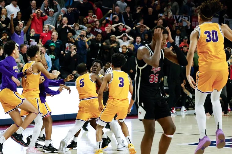 Roman Catholic’s Kabe Goss (center) celebrates his game-winning overtime basket against Archbishop Ryan to clinch the Philadelphia Catholic League boys’ basketball championship.