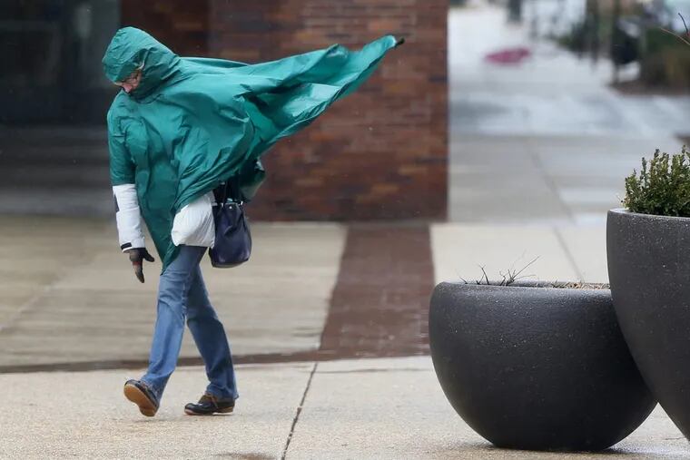 A woman struggles against wind and rain along the Benjamin Franklin Parkway. Winds this month have been impressive.   TIM TAI / Philadelphia Inquirer