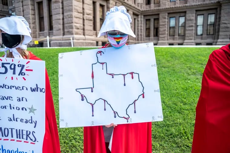 A protester dressed as a handmaiden holds up a sign at a protest outside the Texas state capitol on May 29, 2021, in Austin, Texas. (Sergio Flores/Getty Images/TNS)