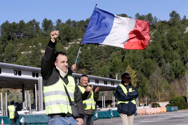 A demonstrators wearing a yellow vest clenches his fist as protesters open the toll gates on a motorway near Aix-en-Provence, southeastern France, Tuesday, Dec. 4, 2018. French Prime Minister Edouard Philippe announced a suspension of fuel tax hikes Tuesday, a major U-turn in an effort to appease a protest movement that has radicalized and plunged Paris into chaos last weekend. (AP Photo/Claude Paris)