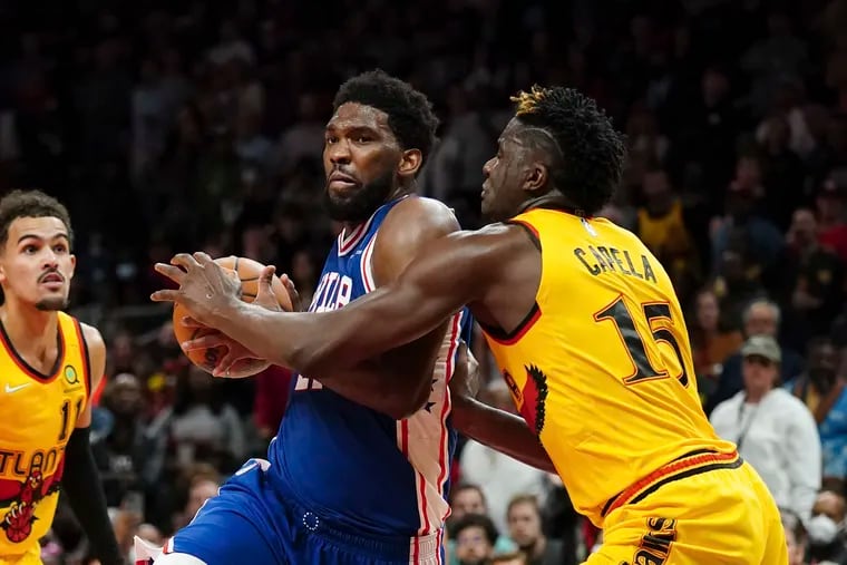 Sixers center Joel Embiid drives to the net with Hawks center Clint Capela defending during the second half Friday night.