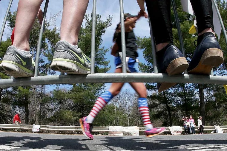 Wellesley College students stand on security barriers as runners pass during the 118th Boston Marathon, Monday, April 21, 2014, in Wellesley, Mass. (AP Photo/Mary Schwalm)