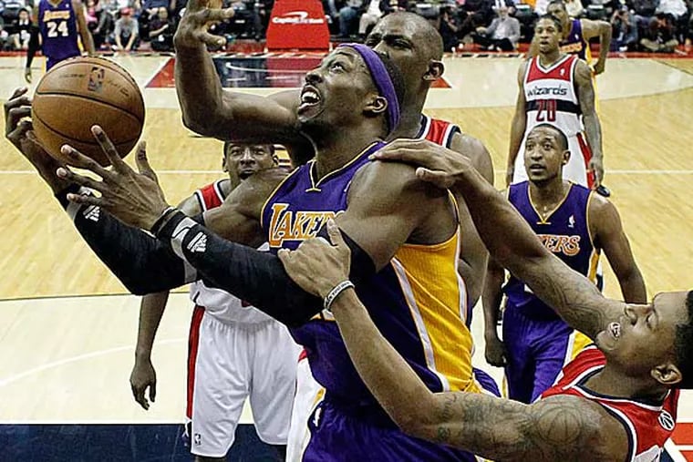Los Angeles Lakers center Dwight Howard is fouled by Washington Wizards forward Kevin Seraphin, top, from France, and guard Bradley Beal, right, in the second half of an NBA basketball game Friday, Dec. 14, 2012 in Washington. (Alex Brandon/AP)