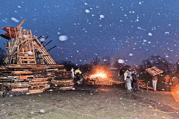 For 11 years, Phoenixville has created a giant bird of wood that it burns as part of a festive winter offering. Vandals set fire to the wooden Phoenix in the early morning hours of Dec. 6, 2014. The townspeople responded by rebuilding it with truckload after truckload of donated wood. The destroyed Phoenix burned all day in several sub-piles alongside the original. (Bob Williams / For The Inquirer)