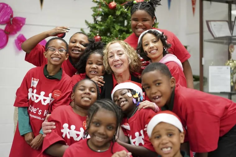 Rubye's Kids founder Roz Weiss poses for a photograph with children during a Christmas Party hosted by Rubye's Kid on Friday at the Richard Wright Elementary School in North Philadelphia.