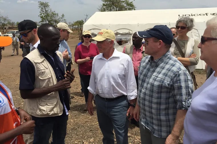 Senators Bob Corker (R-Tenn.), center, and Chris Coons (D-Del.), right, speak with TK PERSON at the Bidi Bidi refugee camp in Uganda.
