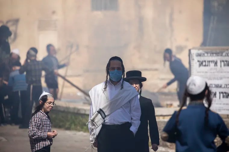 An ultra-Orthodox Jewish man wears a mask as children burn leavened items in final preparation for the Passover holiday in the Orthodox neighborhood of Mea Shearim in Jerusalem.