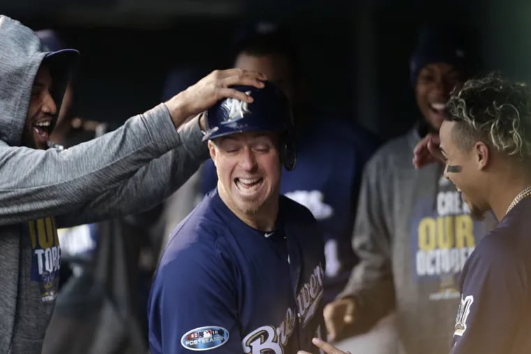 Teammates congratulate Milwaukee Brewers' Erik Kratz as he returns to the dugout after scoring on a wild pitch thrown by Colorado Rockies relief pitcher Scott Oberg in the sixth inning of Game 3 of a baseball National League Division Series Sunday, Oct. 7, 2018, in Denver. (AP Photo)