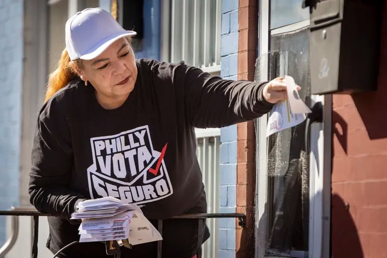 Sonia Pagan places a door hanger information sheet on a house on the 4000 block of North Fairhill Street. She and other volunteers are working with Mijente, a social organization informing members of the Spanish language community on the importance of getting out to vote on Election Day, Nov. 8, 2022.