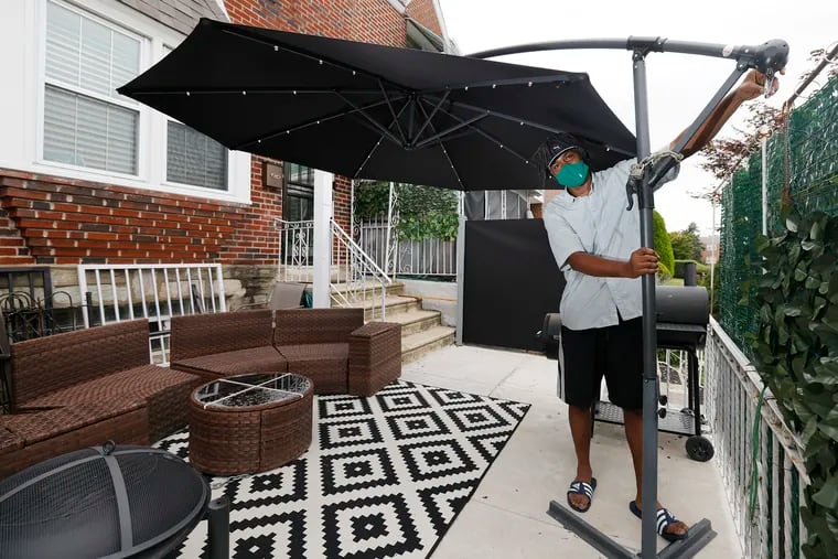 Paul Hall puts up the umbrella that will provide shade for outdoor seating in front of his home in the Cedarbrook section of Philadelphia. The city assessed his home this year as being worth significantly more than he bought it for two years ago, hiking his tax bill.