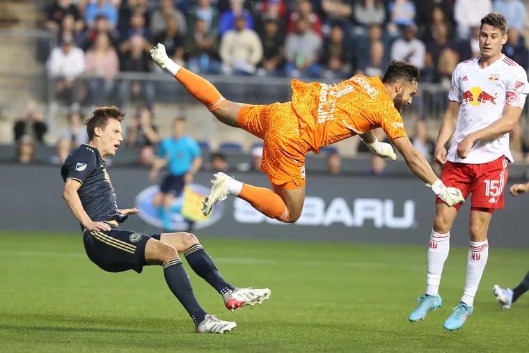 Jack Elliott, left,of the Philadelphia Union and goalkeeper Carlos Coronel of the New York Red Bulls get tangeled up after Coronel stopped a shot during their game on May 14, 2022,  at Subaru Stadium in Chester, PA.