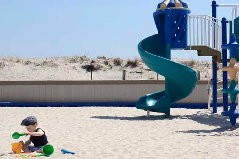 Two year-old Chase Marascio (cq) plays in the playground near 32nd Street where a section of the beach has a sand dune (rear) in Longport April 10, 2013. Longport, formerly opposed to dunes to protect its beach, has changed its mind. Chase was there with this mother, Kristin Marascio (cq). They live year-round in Longport. ( TOM GRALISH / Staff Photographer )