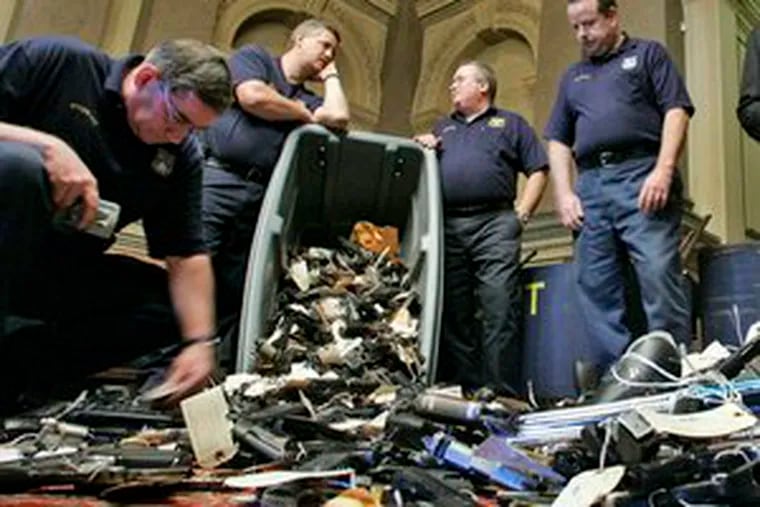 Philadelphia police officers examine handguns after a news conference held yesterday by Chaka Fattah, a U.S. representative and Philadelphia mayoral primary candidate, regarding the &quot;Groceries for Guns Exchange&quot; program. The number of guns turned in is reported at 1,067. Council intends to sue the General Assembly over the right to pass its own gun-control laws.