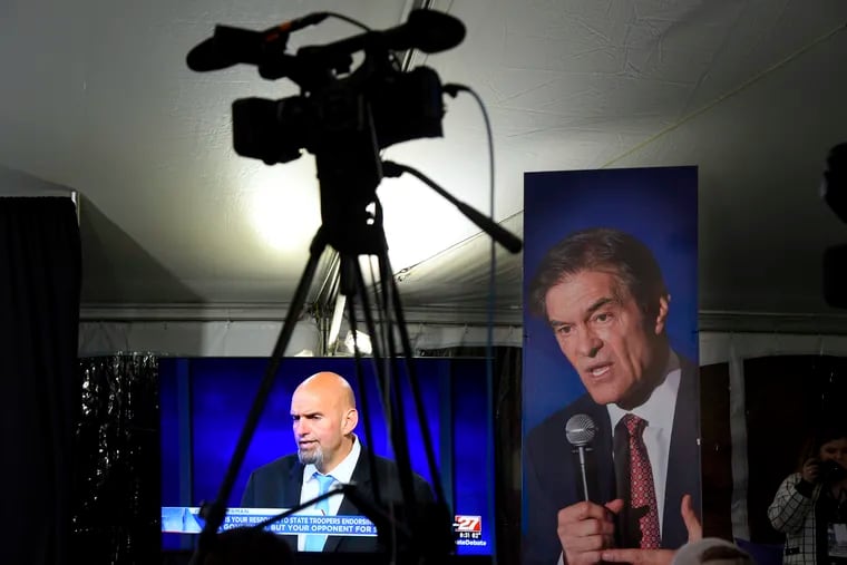 U.S. Senate candidates John Fetterman, on the screen at left, and Mehmet Oz, on the poster, traded jabs on abortion during Tuesday's debate.