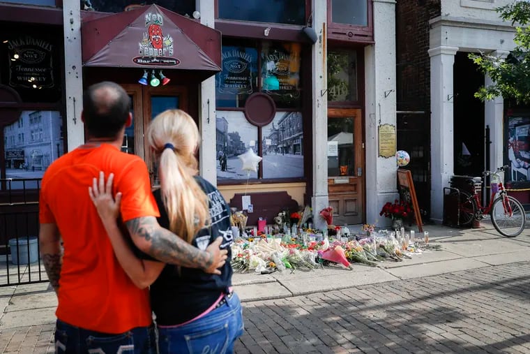 Mourners pause at a makeshift memorial for the slain and injured outside Ned Peppers bar in Dayton, Ohio.
