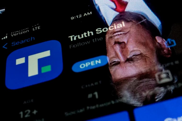 This photo illustration shows an image of former President Donald Trump reflected in a phone screen displaying the Truth Social app.