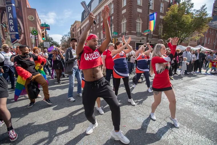 Kareem Anthony (center) dances along with the crowd as he follows a performer on stage holding a Zumba class during Outfest on Sunday.