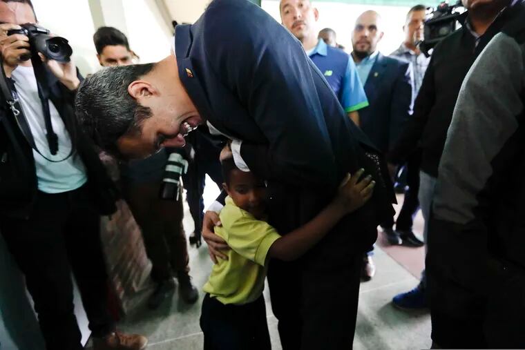 Opposition leader Juan Guaido, who has declared himself interim president of the country, embraces a child at the end of a press conference at a school where he delivered humanitarian aid, in Caracas, Venezuela, Thursday, March 21, 2019. (AP Photo/Natacha Pisarenko)