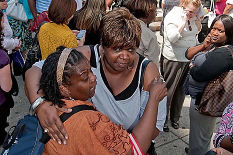 The Rev. Valrita Gordon (left) and Eugenia Fitzhugh hug at LOVE Park after the earthquake forced evacuations of their offices. Gordon works for License and Inspections while Fitzhugh works for the Board of Pensions. (Clem Murray / Staff)