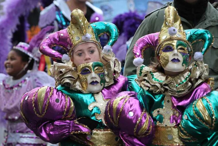 Kailee Didominic, left, takes her mask off to see the signal to move up to street to perform in the Fancy Brigade of Hog Island. She is part of the "Jesters" in the Fancy Brigade.( MICHAEL BRYANT / Staff Photographer )