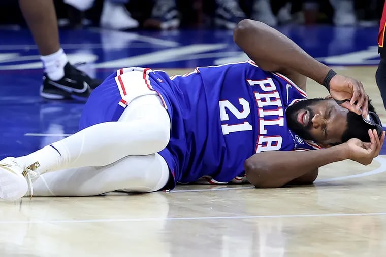 Joel Embiid of the Sixers llies on the court after a hard foul by Bam Adebayo of the Heat during the 2nd half of their playoff game at the Wells Fargo Center on May 6, 2022.