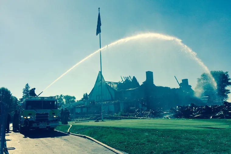 Fire crews continue to douse the shouldering remains of the Lulu Country Club in Upper Dublin Township, Montgomery County.