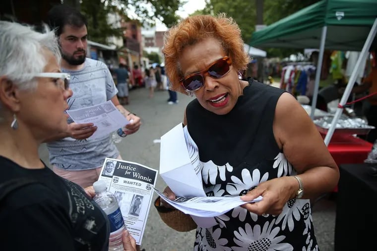 Saundra Fulwood, right, hands out fliers of the two people of interest police are seeking in the death of West Philly community activist Winnie Harris at the Lancaster Avenue Arts and Jazz Festival in Powelton on July 15, 2017.