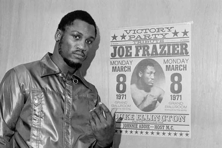 Joe Frazier poses by a poster advertising his "victory party" after a workout in Philadelphia in 1971 ahead of his famous bout with Muhammad Ali.