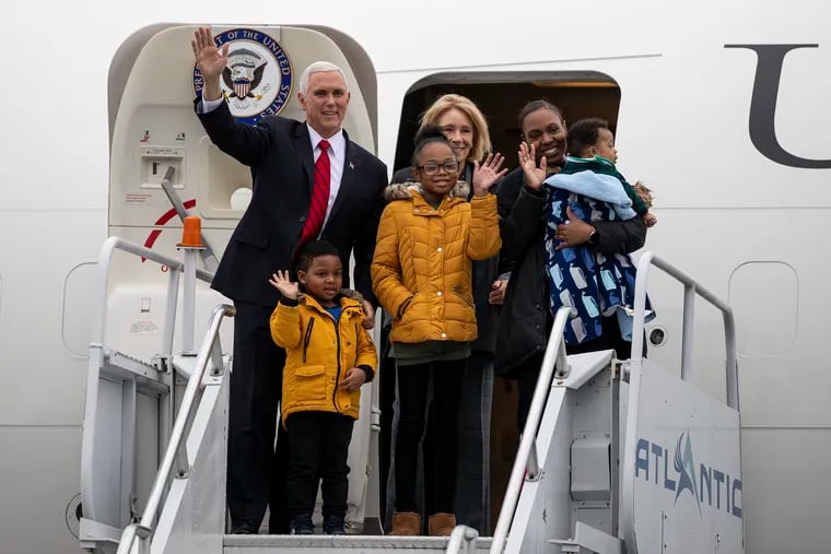 Vice President Mike Pence and Secretary of Education Betsy DeVos, behind, wave to supporters with Philadelphia mother Stephanie Davis and her children, including daughter Janiyah Davis, center, after landing at the Philadelphia International Airport.