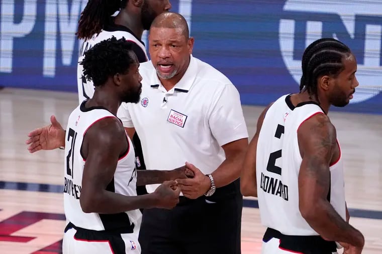 Los Angeles Clippers head coach Doc Rivers, center, talks with Los Angeles Clippers' Patrick Beverley (21) after their win over the Denver Nuggets in an NBA conference semifinal playoff basketball game Monday, Sept. 7, 2020, in Lake Buena Vista, Fla. (AP Photo/Mark J. Terrill)