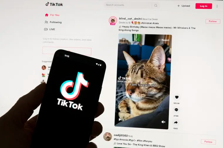 The TikTok logo is seen on a mobile phone in front of a computer screen which displays the TikTok home screen. The U.S. Senate passed legislation Tuesday that will require a sale of the company to avoid a ban in the country.