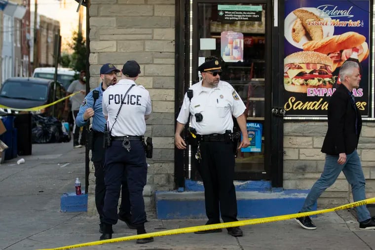 Police stand at the scene of a shooting inside the corner store at 20th and Federal Streets in the Point Breeze section of Philadelphia on May 13.