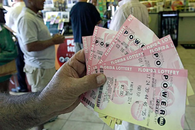 Robert Brent holds up the Powerball tickets he purchased as customers line up to buy theirs at a convenience store Tuesday, Nov. 27, 2012, in Orlando, Fla. The powerball jackpot is up over $500 million for Wednesday's drawing. (AP Photo/John Raoux)