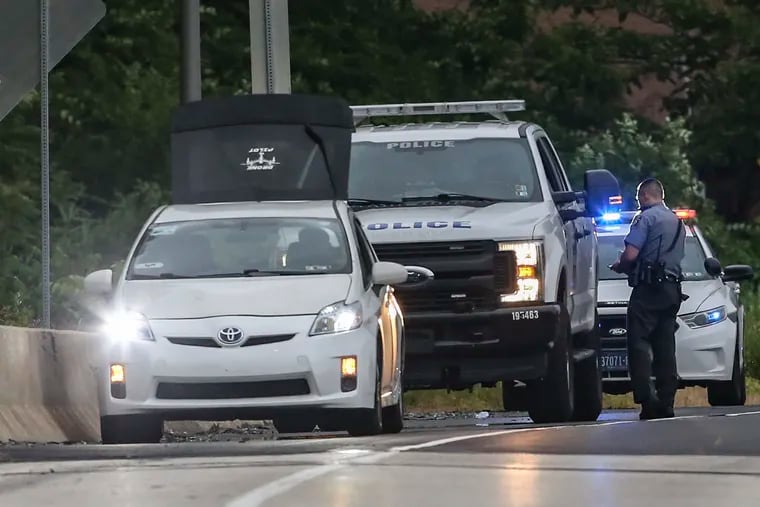 Pennsylvania State Police and Philadelphia city police behind a white Toyota Prius that was struck by gunfire during a possible road-rage attack on the Schuylkill Expressway near the Montgomery Drive exit, June 22, 2022.