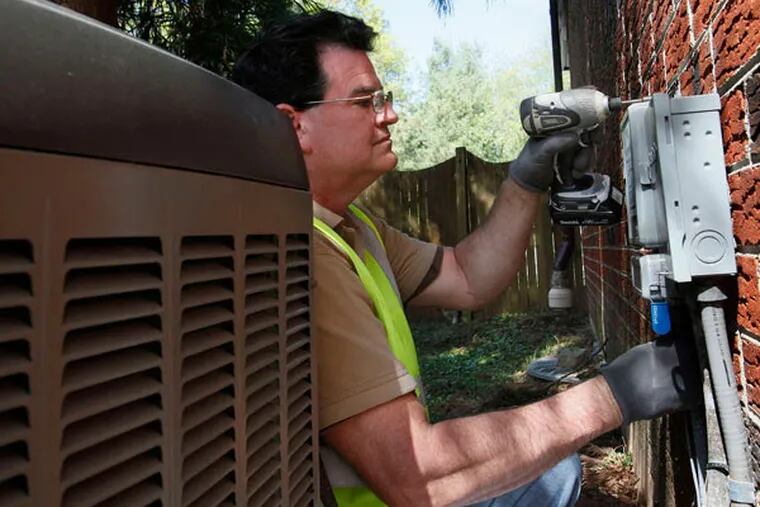 Michael P. King , a Peco field technician, installing a digital cycling unit near a house's central-air unit last year. (Michael S. Wirtz / Staff Photographer)